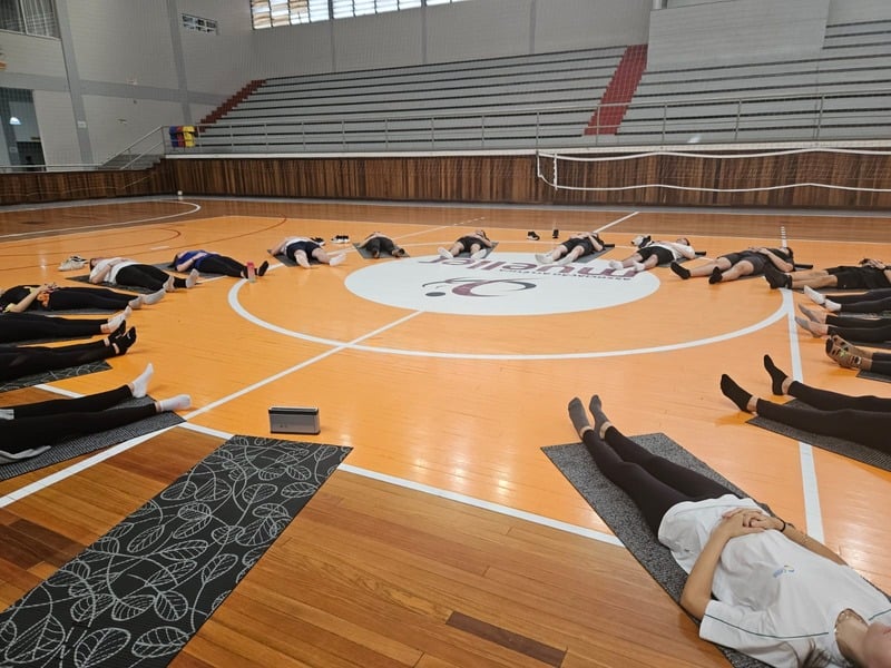 Grupo de estudantes praticando yoga em um ginásio